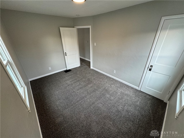 unfurnished bedroom with dark carpet