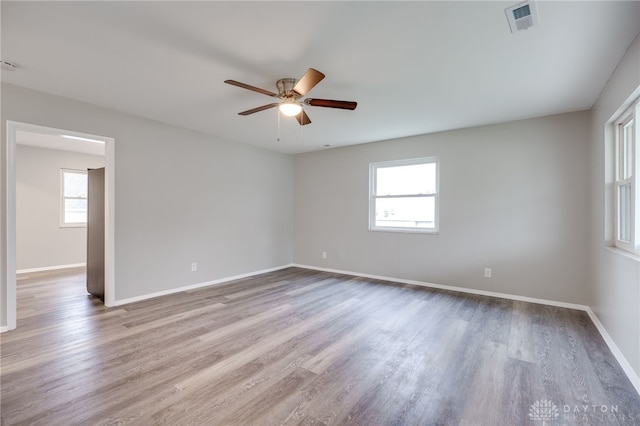 empty room featuring a wealth of natural light, light hardwood / wood-style flooring, and ceiling fan