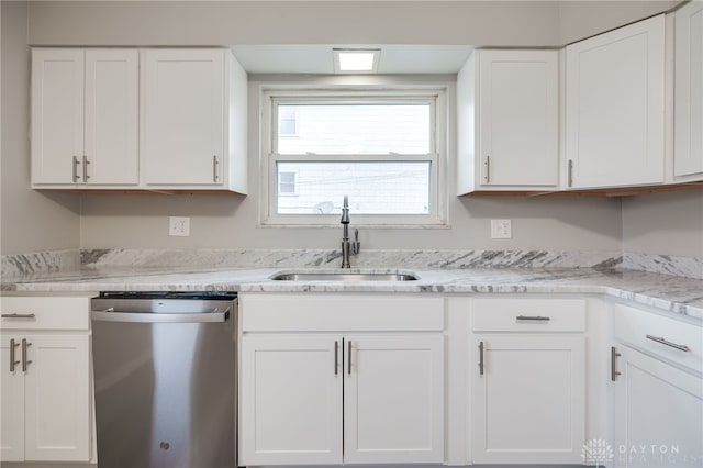 kitchen featuring light stone countertops, white cabinetry, stainless steel dishwasher, and sink