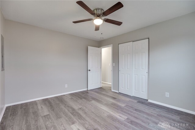 unfurnished bedroom featuring ceiling fan, a closet, and light wood-type flooring