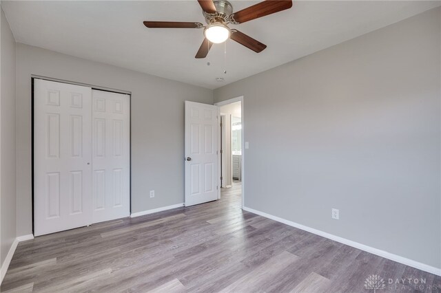 unfurnished bedroom with ceiling fan, a closet, and light wood-type flooring