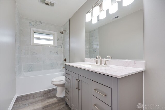 full bathroom with vanity, toilet, wood-type flooring, and tiled shower / bath