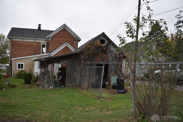 back of house featuring a lawn and an outdoor structure