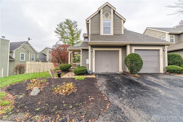 traditional-style home featuring a garage, roof with shingles, fence, and driveway