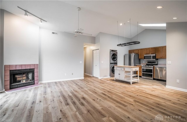 kitchen with a fireplace, visible vents, open floor plan, appliances with stainless steel finishes, and stacked washer and clothes dryer