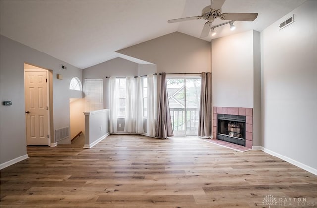 unfurnished living room featuring vaulted ceiling, a fireplace, wood finished floors, and visible vents