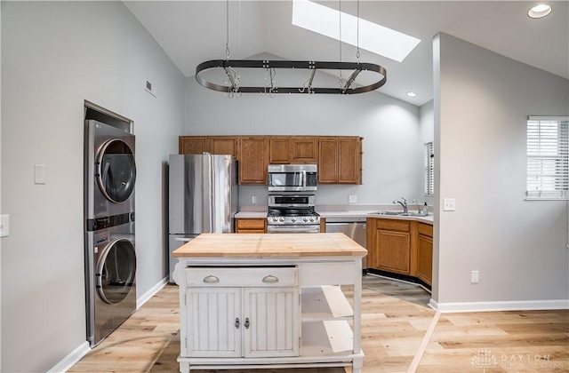 kitchen with wooden counters, appliances with stainless steel finishes, light wood-type flooring, and stacked washing maching and dryer