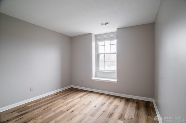 unfurnished room featuring light wood-type flooring, visible vents, and baseboards