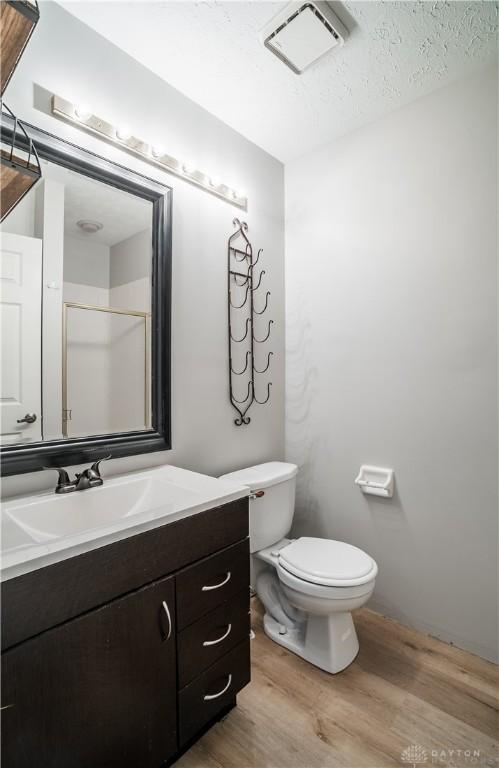 full bath featuring visible vents, toilet, wood finished floors, walk in shower, and vanity