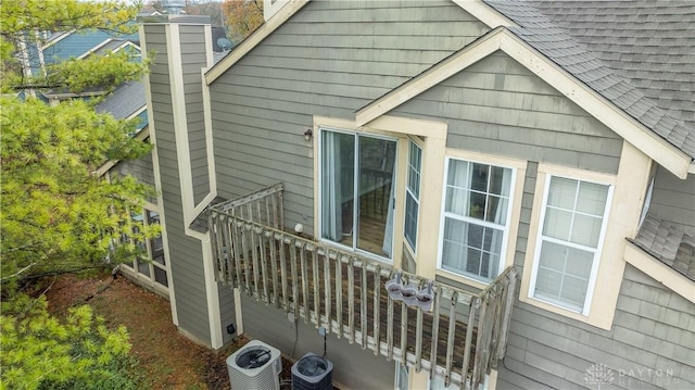 view of side of home featuring a shingled roof and central AC unit