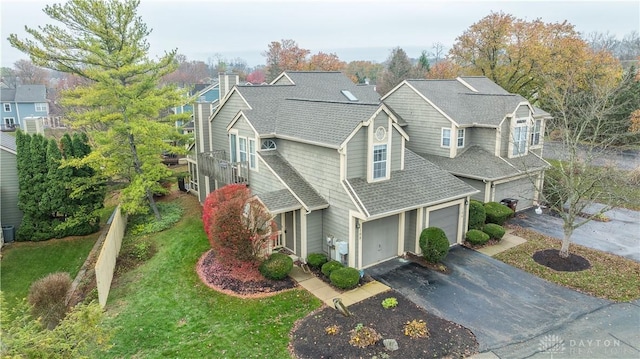 view of front of property with aphalt driveway, an attached garage, roof with shingles, a front lawn, and a chimney