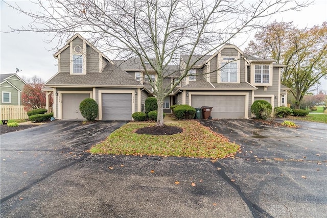 view of front of house with a garage, aphalt driveway, and roof with shingles