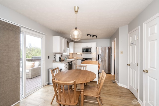 dining area featuring a textured ceiling, light hardwood / wood-style flooring, and sink