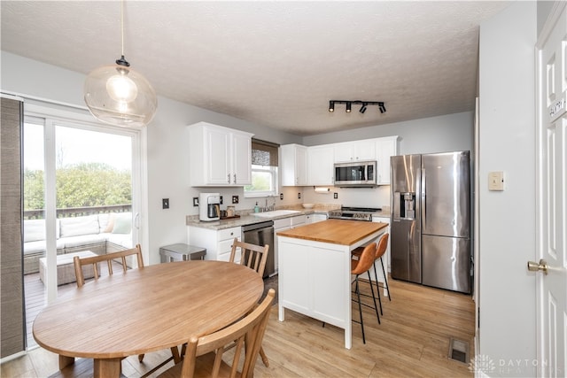 kitchen featuring a center island, sink, light hardwood / wood-style flooring, white cabinets, and appliances with stainless steel finishes