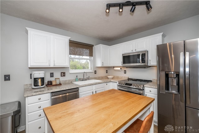 kitchen with a textured ceiling, sink, white cabinetry, and stainless steel appliances