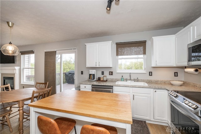 kitchen featuring white cabinets, light wood-type flooring, stainless steel appliances, and sink