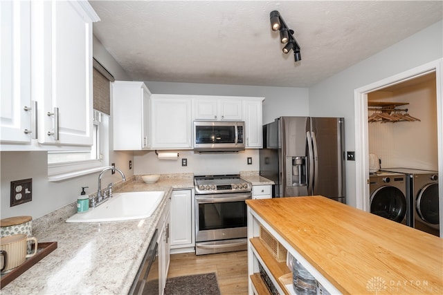 kitchen featuring white cabinets, sink, separate washer and dryer, light hardwood / wood-style floors, and stainless steel appliances