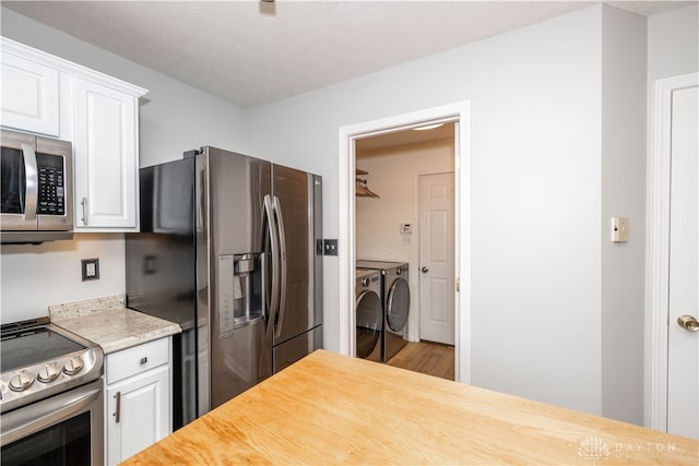 kitchen featuring hardwood / wood-style floors, separate washer and dryer, a textured ceiling, white cabinetry, and stainless steel appliances