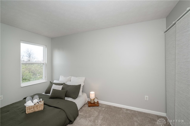 carpeted bedroom featuring a textured ceiling and a closet