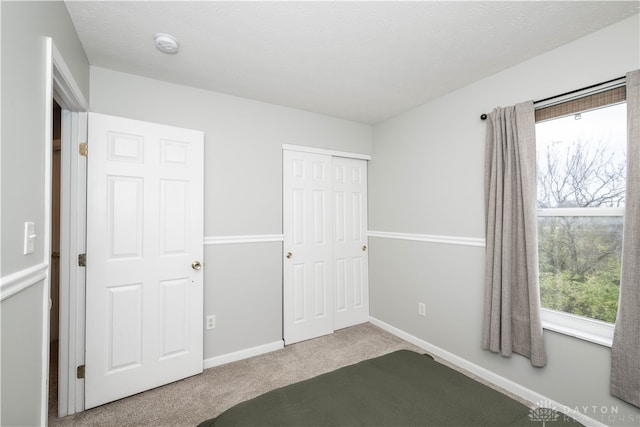 unfurnished bedroom with carpet flooring, a textured ceiling, and a closet