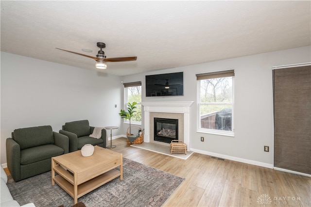 living room featuring a healthy amount of sunlight, ceiling fan, wood-type flooring, and a textured ceiling