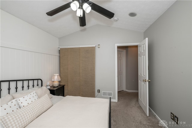 carpeted bedroom with a textured ceiling, ceiling fan, and lofted ceiling