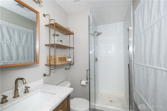 bathroom featuring a shower with door, vanity, a textured ceiling, and toilet