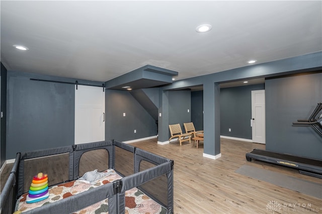 exercise room featuring a barn door and light hardwood / wood-style flooring