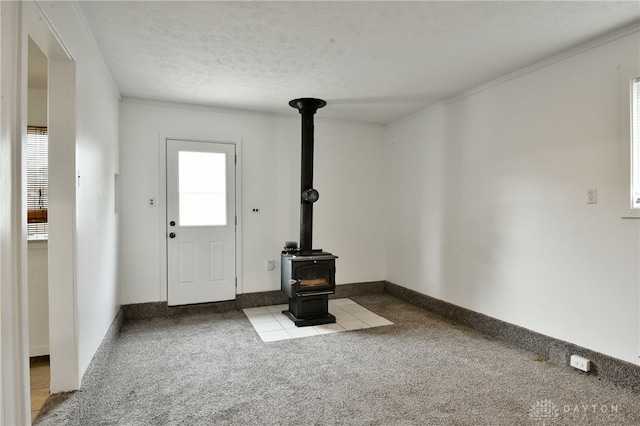 unfurnished living room featuring light carpet, a textured ceiling, a wood stove, and crown molding