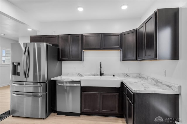 kitchen featuring light stone counters, sink, appliances with stainless steel finishes, and light hardwood / wood-style flooring