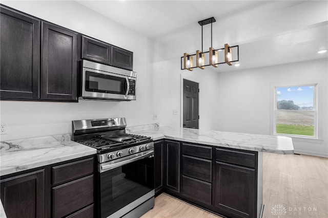 kitchen with kitchen peninsula, hanging light fixtures, stainless steel appliances, and light hardwood / wood-style floors