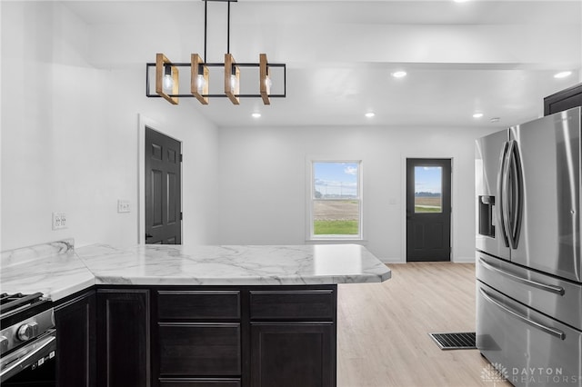 kitchen featuring stainless steel appliances, an inviting chandelier, kitchen peninsula, pendant lighting, and light wood-type flooring