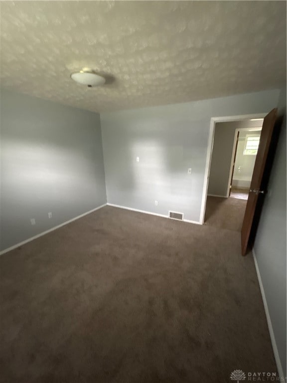 carpeted empty room featuring a textured ceiling