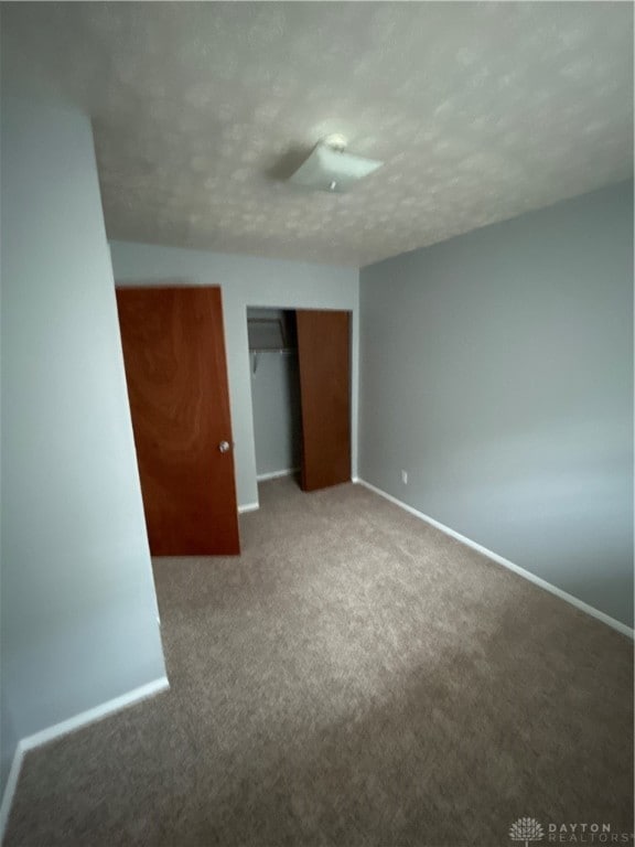 unfurnished bedroom featuring carpet floors, a closet, and a textured ceiling