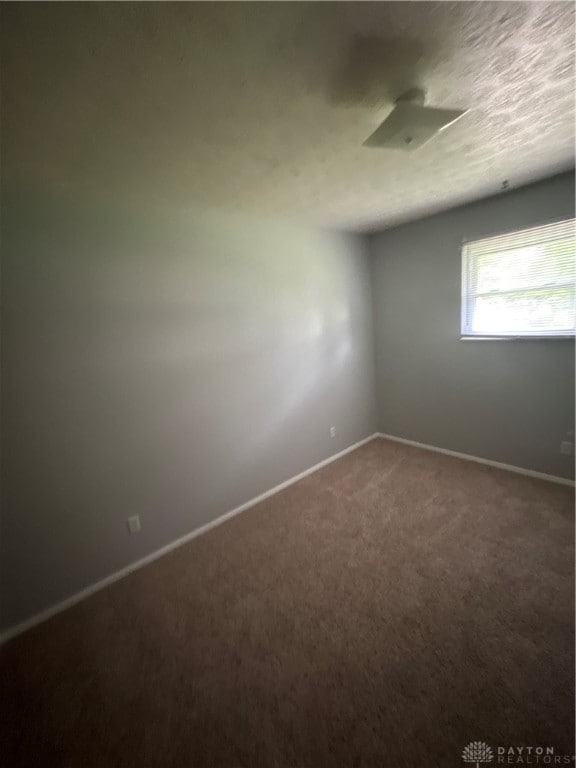 carpeted spare room with a textured ceiling