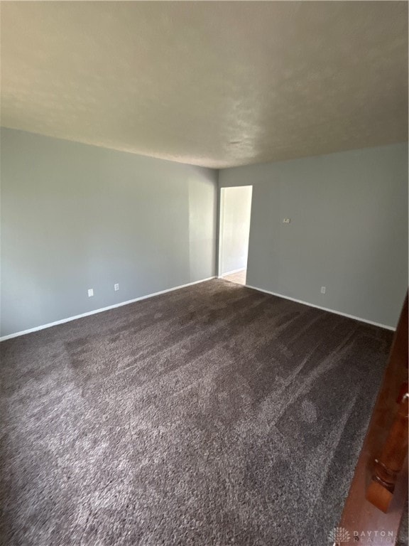 unfurnished room with dark colored carpet