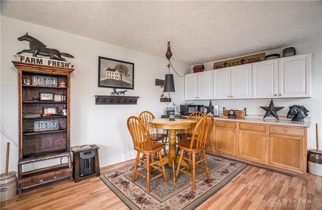 dining room featuring a textured ceiling and light hardwood / wood-style flooring