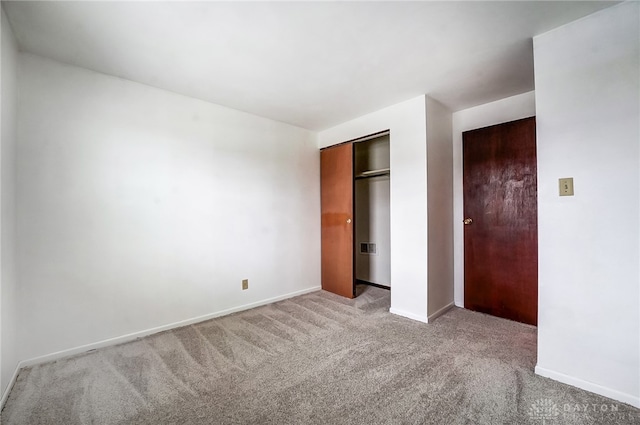 unfurnished bedroom with light carpet and a closet