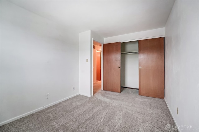 unfurnished bedroom with light colored carpet and a closet