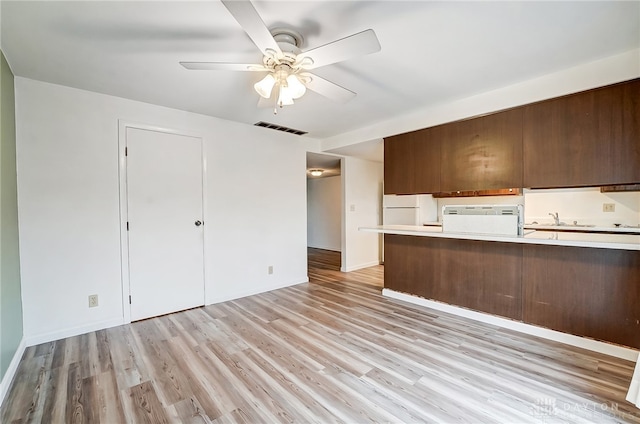 kitchen with white appliances, sink, light hardwood / wood-style flooring, ceiling fan, and kitchen peninsula