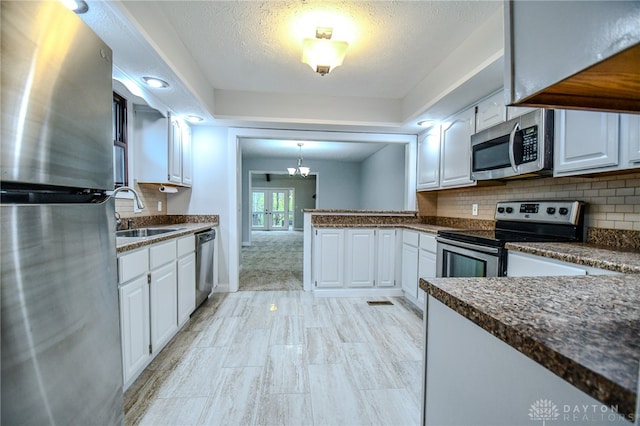 kitchen featuring tasteful backsplash, appliances with stainless steel finishes, a textured ceiling, white cabinetry, and a sink