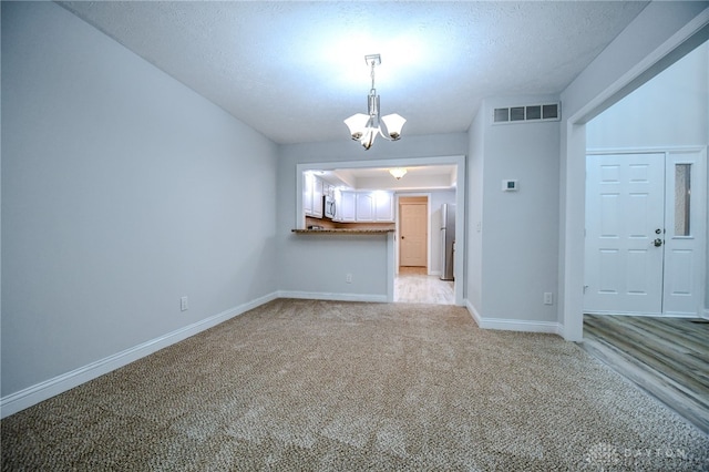 interior space featuring light colored carpet, a chandelier, and a textured ceiling