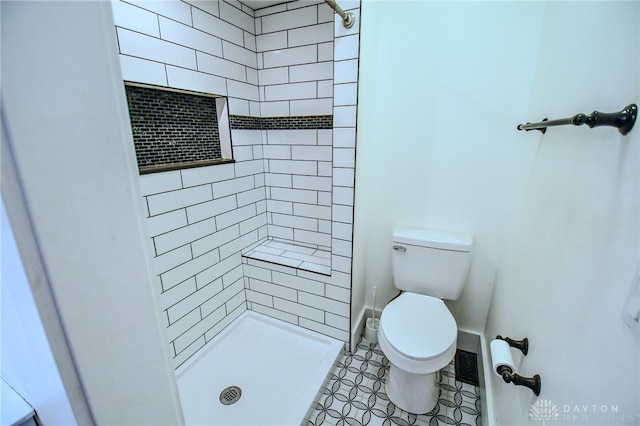 bathroom featuring a tile shower and toilet