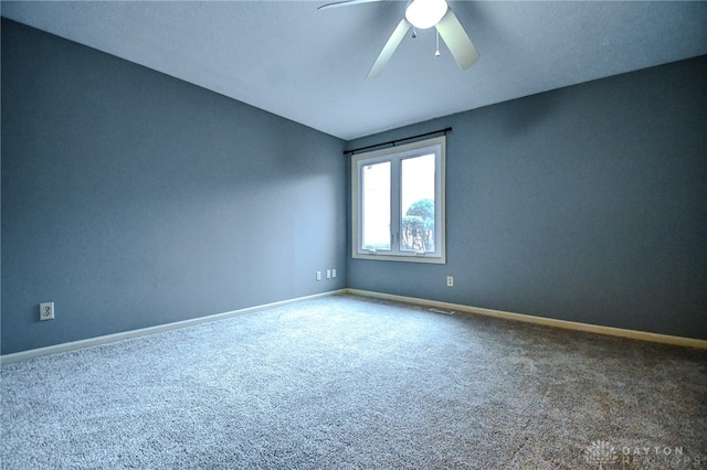 unfurnished room with carpet floors, visible vents, baseboards, and a ceiling fan