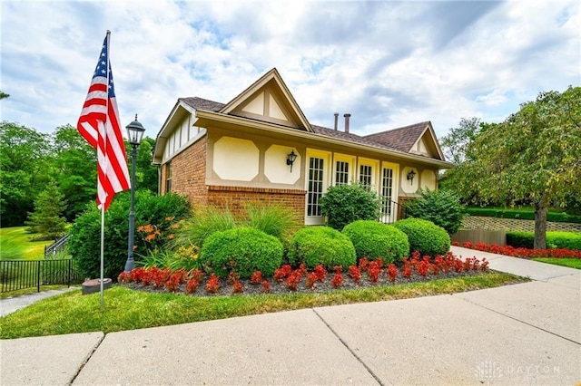 view of front of home featuring stucco siding, brick siding, and fence