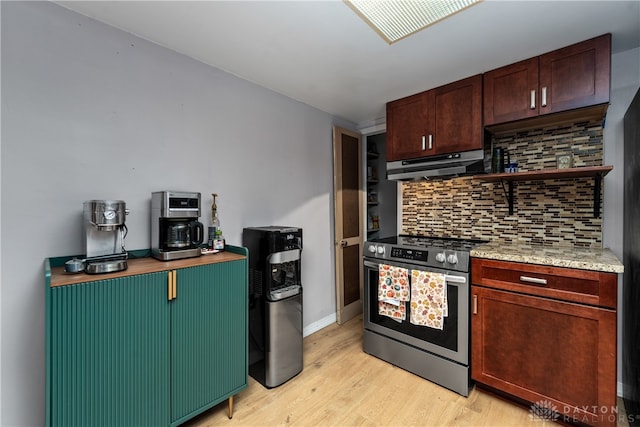 kitchen with backsplash, light stone countertops, high end range, and light hardwood / wood-style floors