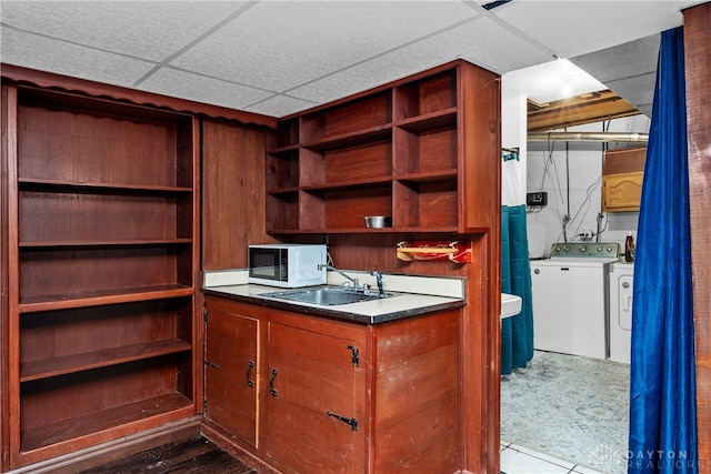 interior space featuring a paneled ceiling, separate washer and dryer, and sink