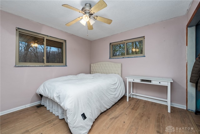 bedroom featuring hardwood / wood-style flooring, ceiling fan, and a textured ceiling