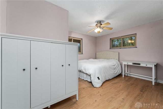 bedroom featuring ceiling fan, light wood-type flooring, and a textured ceiling