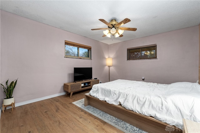 bedroom with a textured ceiling, hardwood / wood-style flooring, and ceiling fan